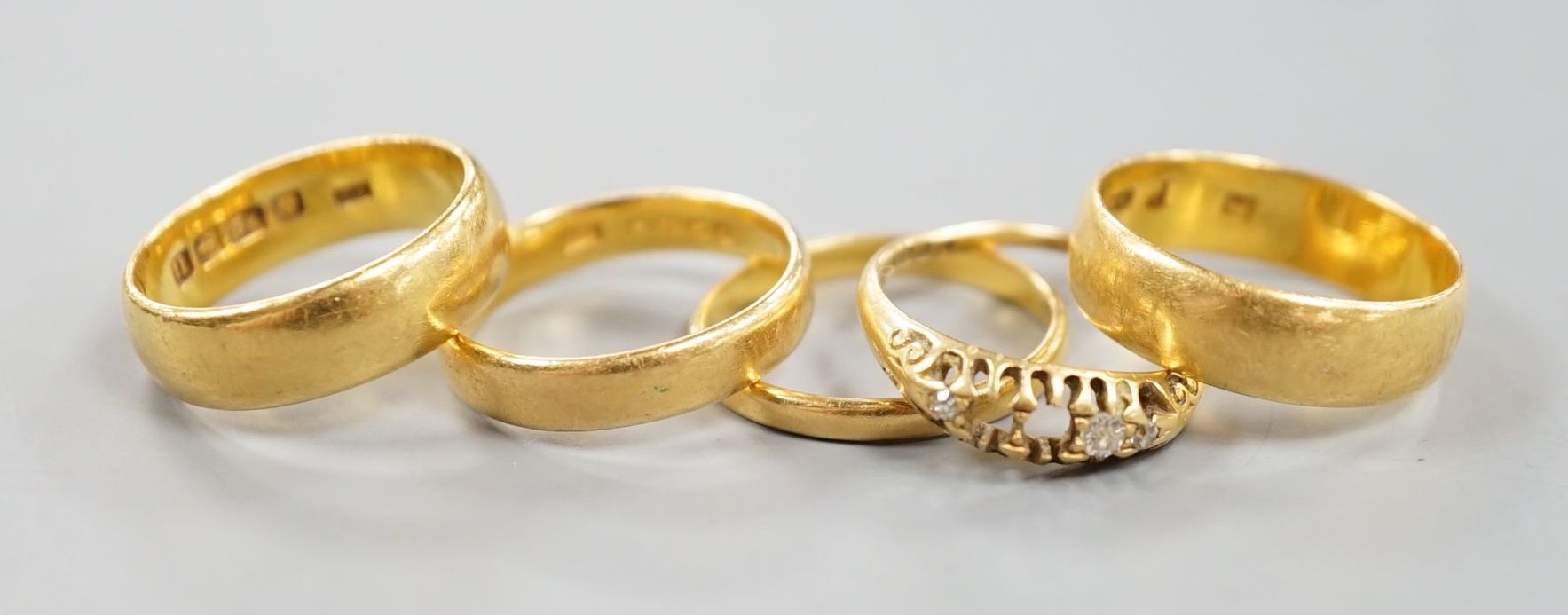 Four assorted mainly early 20th century 22ct gold wedding bands and an 18ct and diamond chip set ring(stones missing